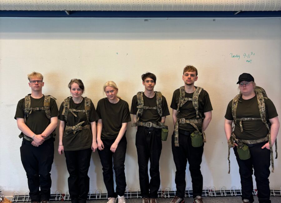 Elever står på række med rygsække og uniform