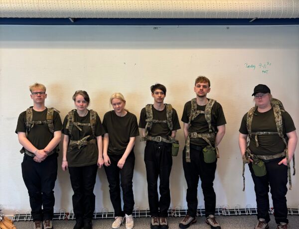Elever står på række med rygsække og uniform