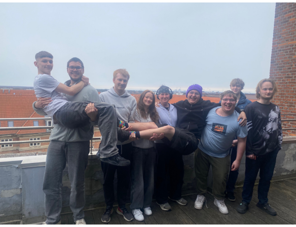 Gruppe af elever står samlet på en tagterrasse og smiler til kameraet.