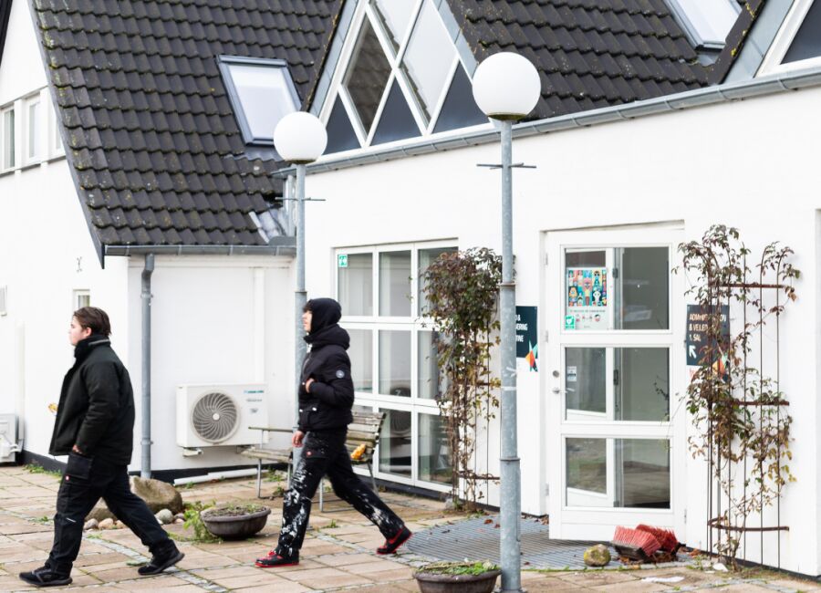 To personer går foran FGU-skolens hvide bygning i Svebølle med store tagvinduer og mørkt tegltag.