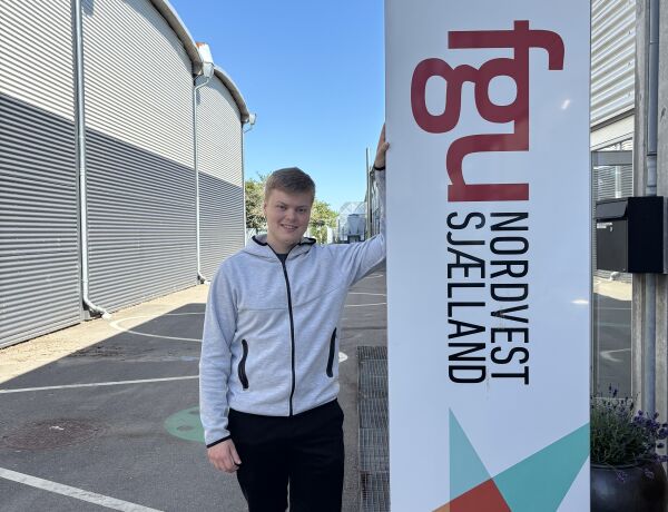 Tobias Bastholm står ved skiltet foran FGU Nordvestsjælland i Holbæk.