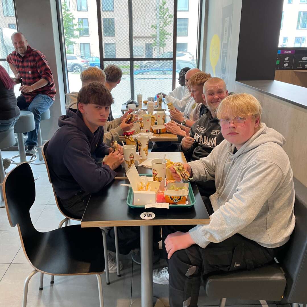 Elever og undervisere spiser frokost sammen efter besøget hos Nørgaard Teknik A/S.