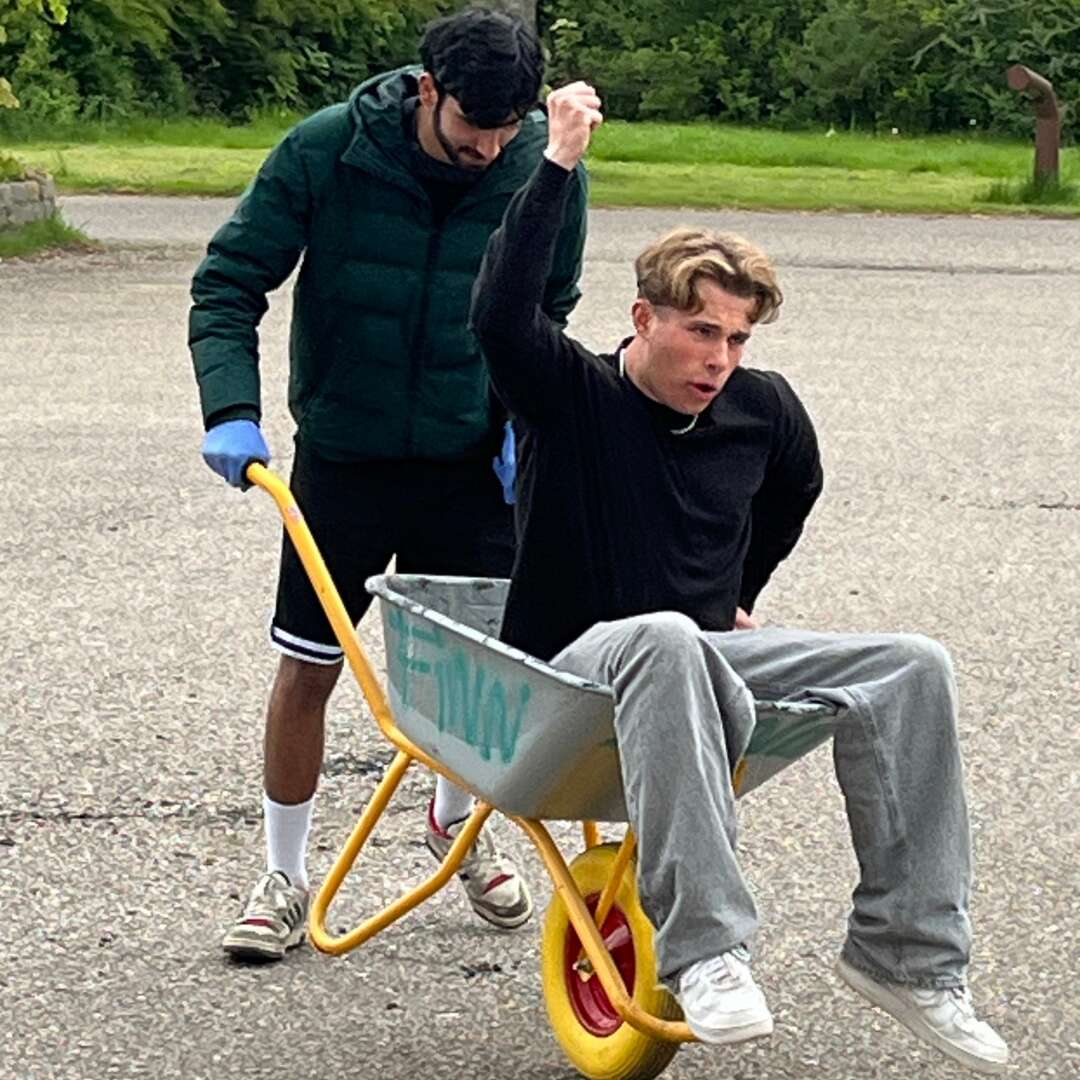 To elever laver sjov med en trillebør under udendørs aktivitet.