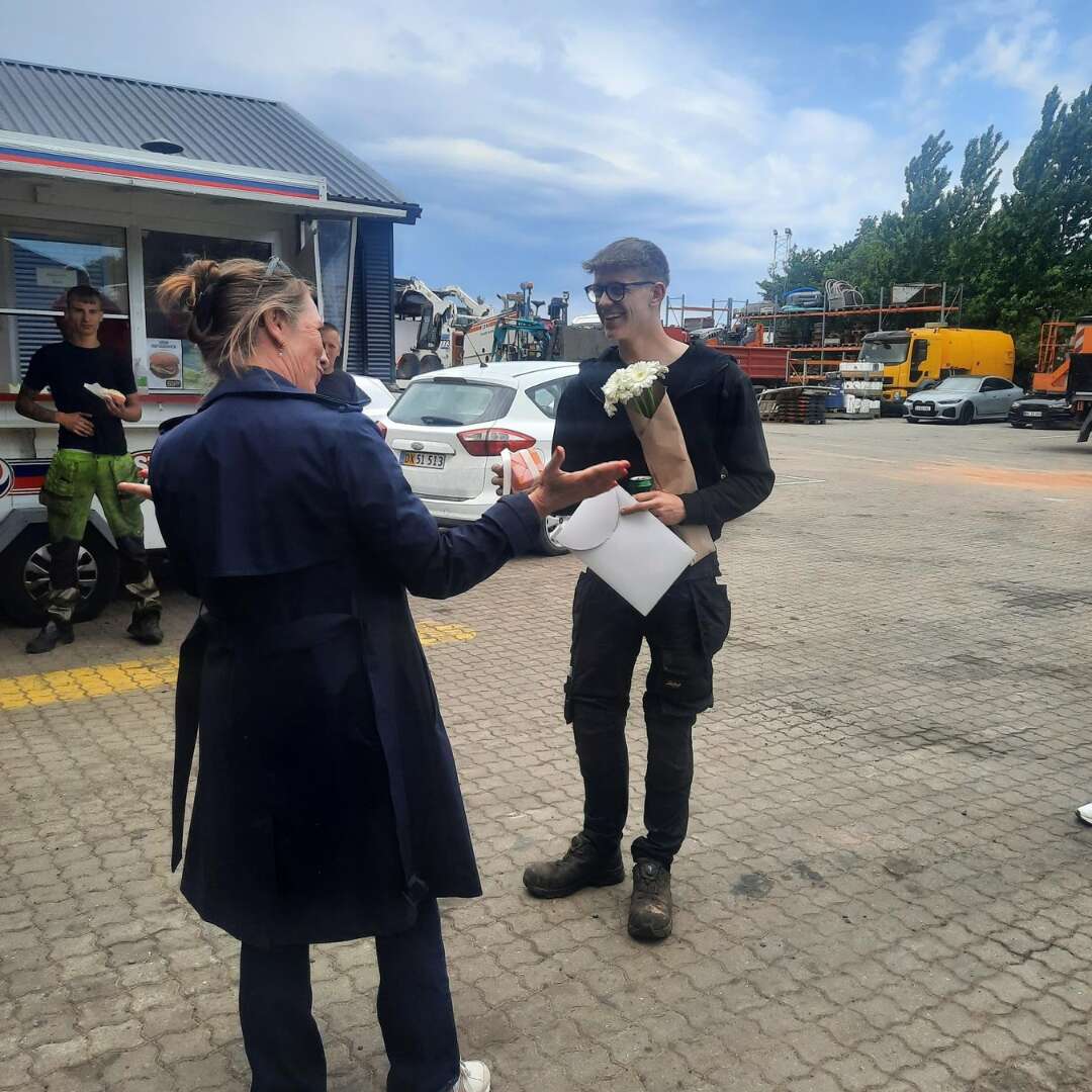 Romeo modtager blomster og lykønskninger efter sin beståede fagprøve hos Dansk Asfalt.