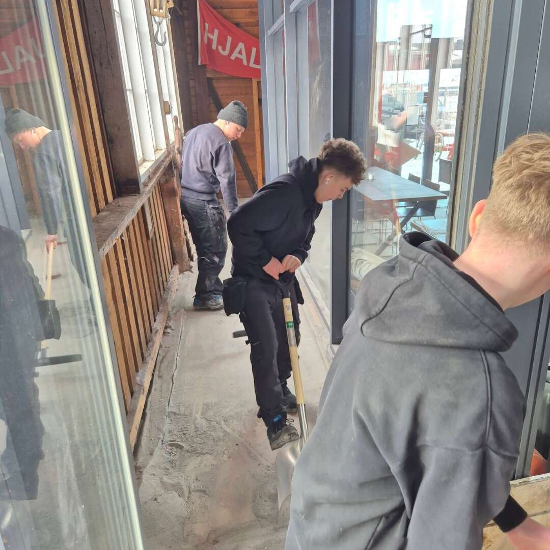 Elever rydder sand og klargør glasburene på havnen til festivalen.