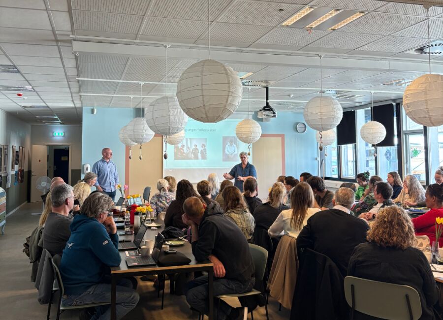 Kursister og medarbejdere arbejder i grupper ved borde under en fælles øvelse på kursusdagen.