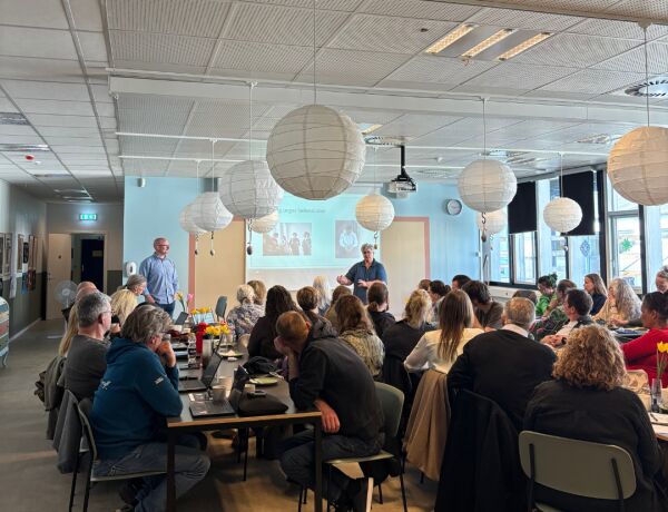 Kursister og medarbejdere arbejder i grupper ved borde under en fælles øvelse på kursusdagen.